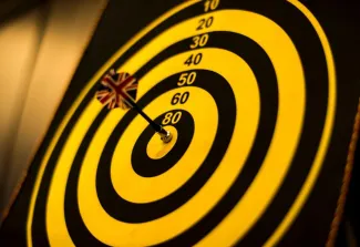 A dart is perfectly positioned in the center of a bullseye target, symbolizing precision and accuracy.