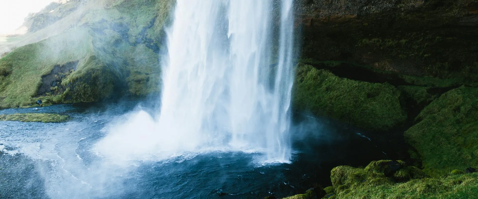 Stunning view of Kjöllvík waterfall in Iceland, flowing powerfully down rocky terrain amidst vibrant natural scenery.