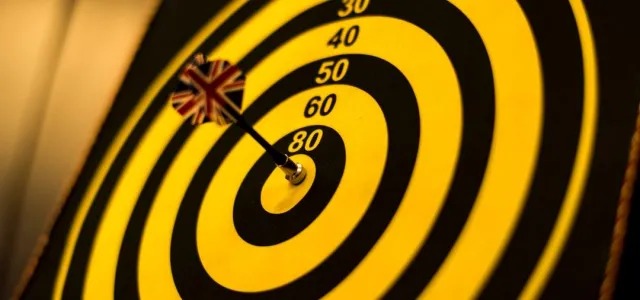 A dart is perfectly positioned in the center of a bullseye target, symbolizing precision and accuracy.
